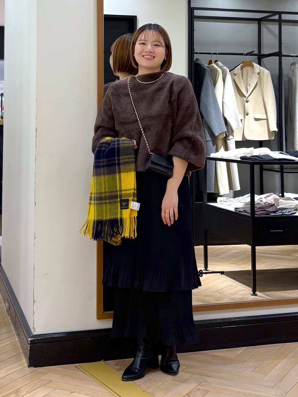 ブラック系のブーツ、ブラック系のスカート、ブラウン系のニット/セーターを着用したレディースの冬コーディネートの2枚目の写真