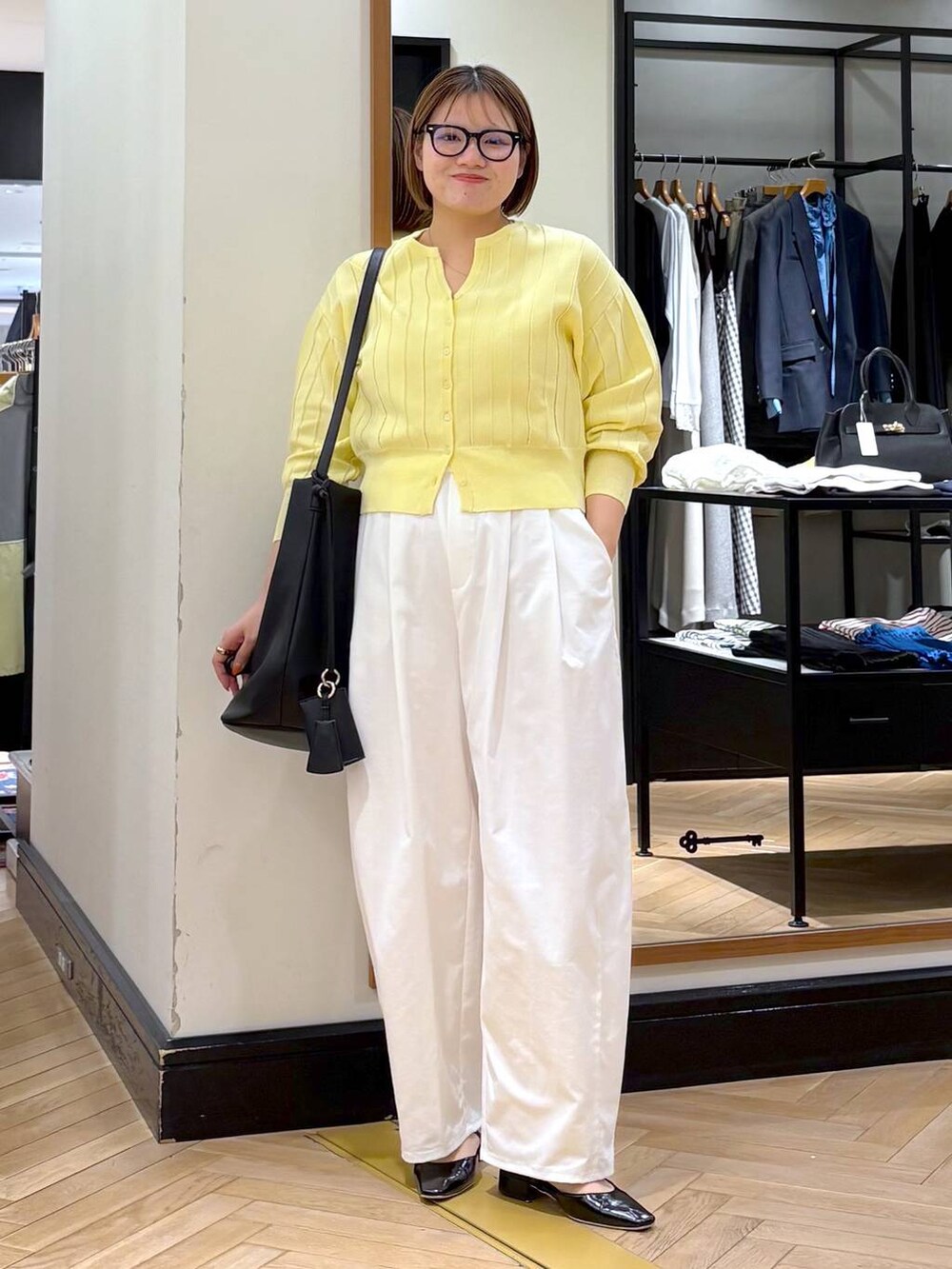 イエロー系のカーディガン/ボレロ、ブラック系のトートバッグ、ブラック系のパンプスを着用したレディースの春コーディネートの2枚目の写真