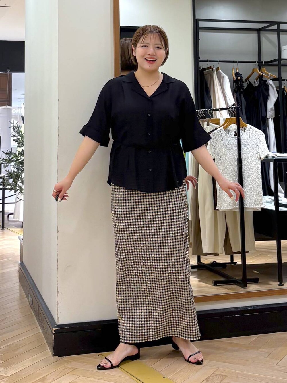 ブラック系のサンダル、ホワイト系のスカート、ブラック系のシャツ/ブラウスを着用したレディースの夏コーディネートの3枚目の写真