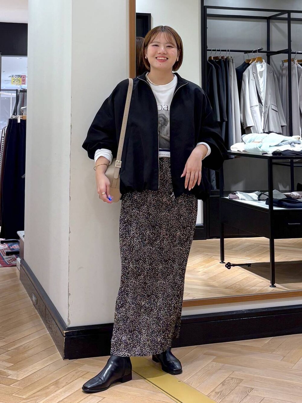 ブラウン系のスカート、ブラック系のブルゾン、ブラック系のブーツを着用したレディースの秋コーディネートの2枚目の写真