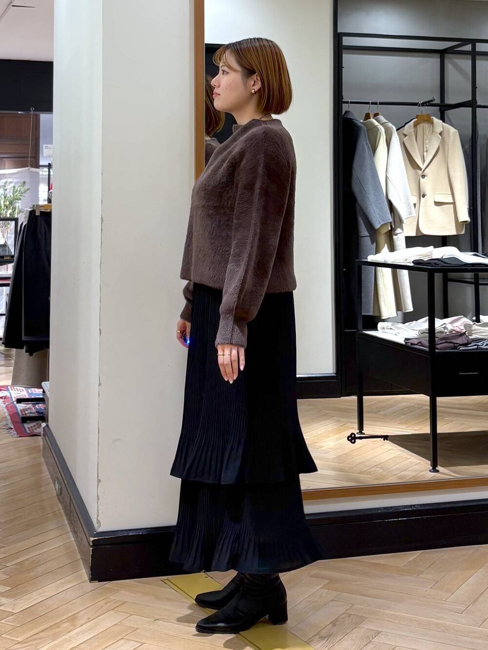 ブラック系のブーツ、ブラック系のスカート、ブラウン系のニット/セーターを着用したレディースの冬コーディネートの6枚目の写真