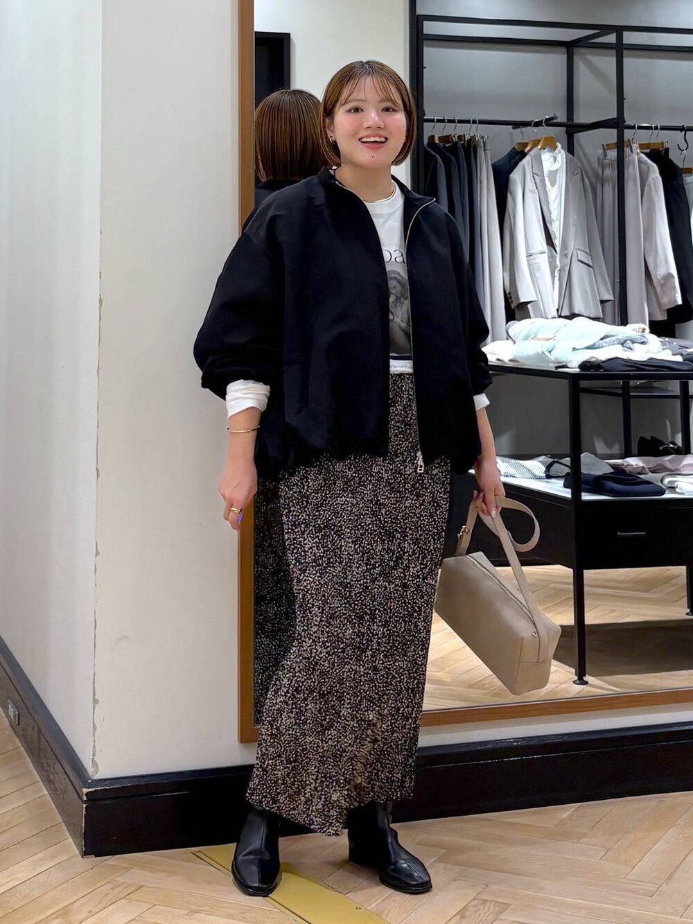 ブラウン系のスカート、ブラック系のブルゾン、ブラック系のブーツを着用したレディースの秋コーディネートの6枚目の写真