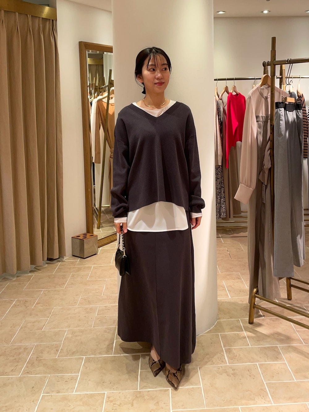 ホワイト系のシャツ/ブラウス、グレー系のニット/セーター、グレー系のスカートを着用したレディースの冬コーディネートの2枚目の写真