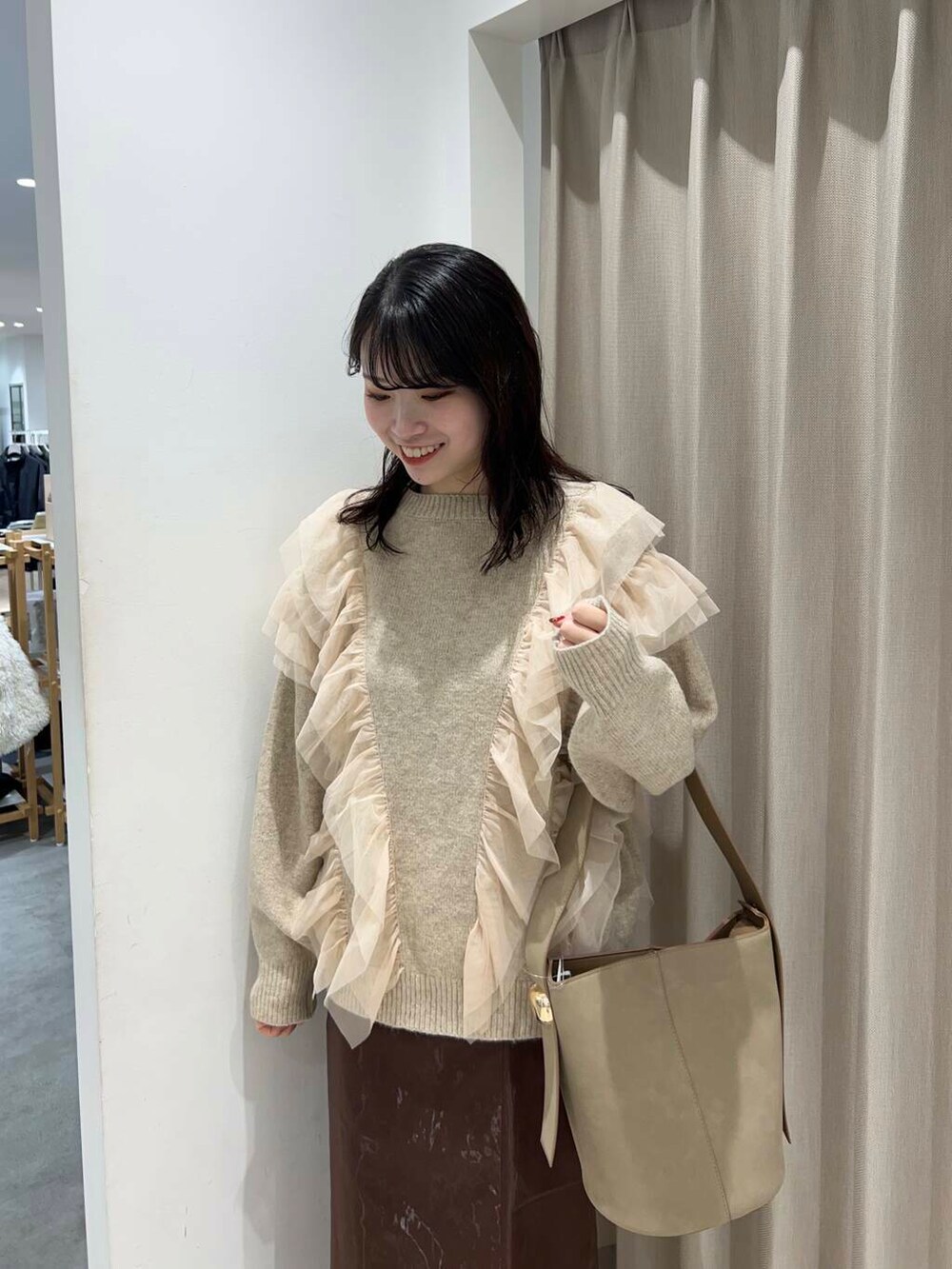 ベージュ系のハンドバッグ、ブラック系のブーツ、ブラウン系のスカートを着用したレディースの冬コーディネートの4枚目の写真