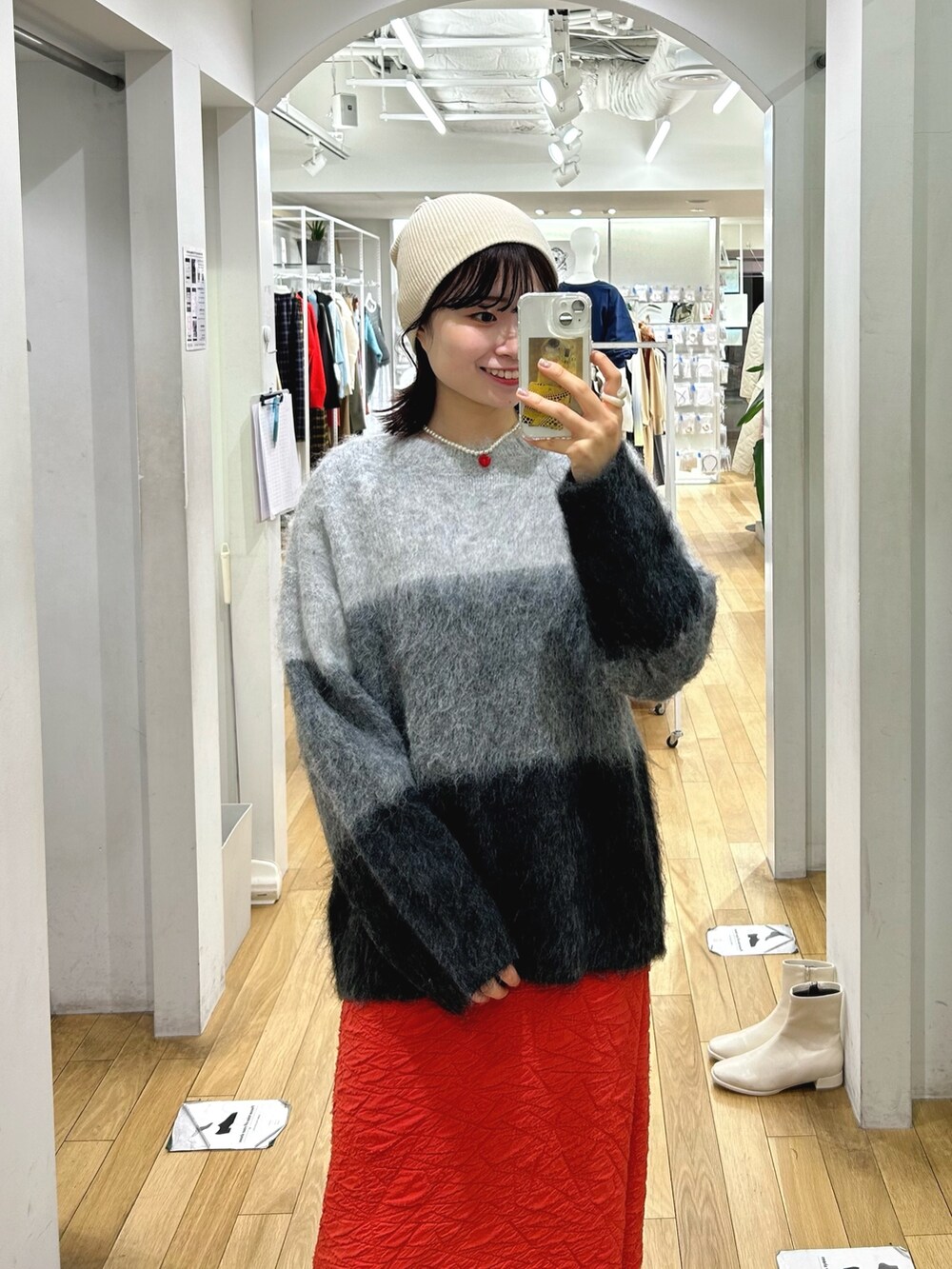 グレー系のニット/セーター、レッド系のスカート、イエロー系のショルダーバッグを着用したレディースの冬コーディネートの3枚目の写真