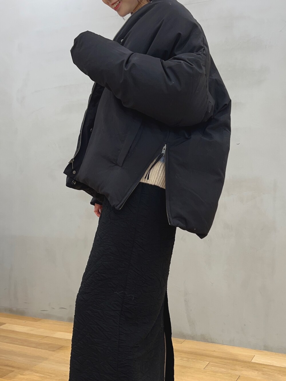 ブラック系のスカート、ブルー系のニット/セーター、ブラック系のダウンジャケット/コートを着用したレディースの冬コーディネートの3枚目の写真