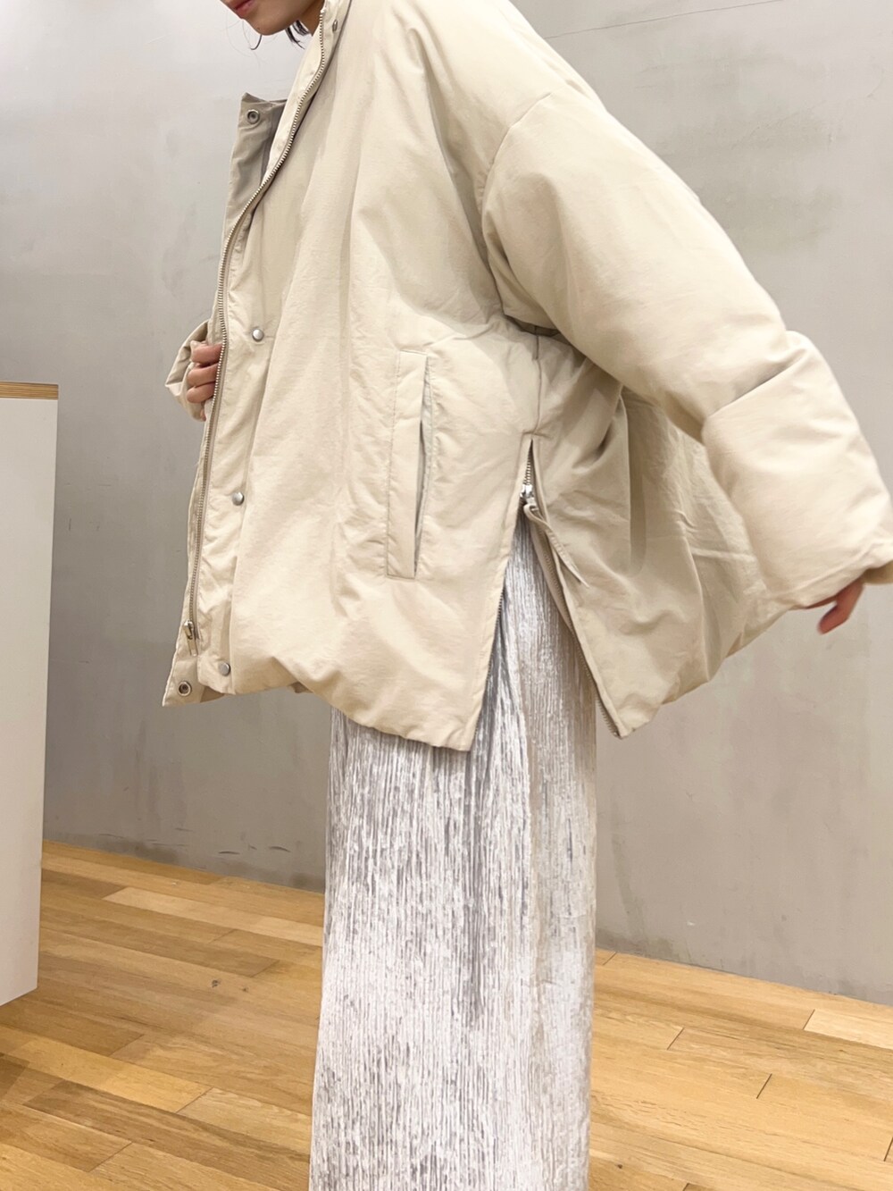 グレー系のスカート、ベージュ系のダウンジャケット/コート、グレー系のカーディガン/ボレロを着用したレディースの冬コーディネートの3枚目の写真