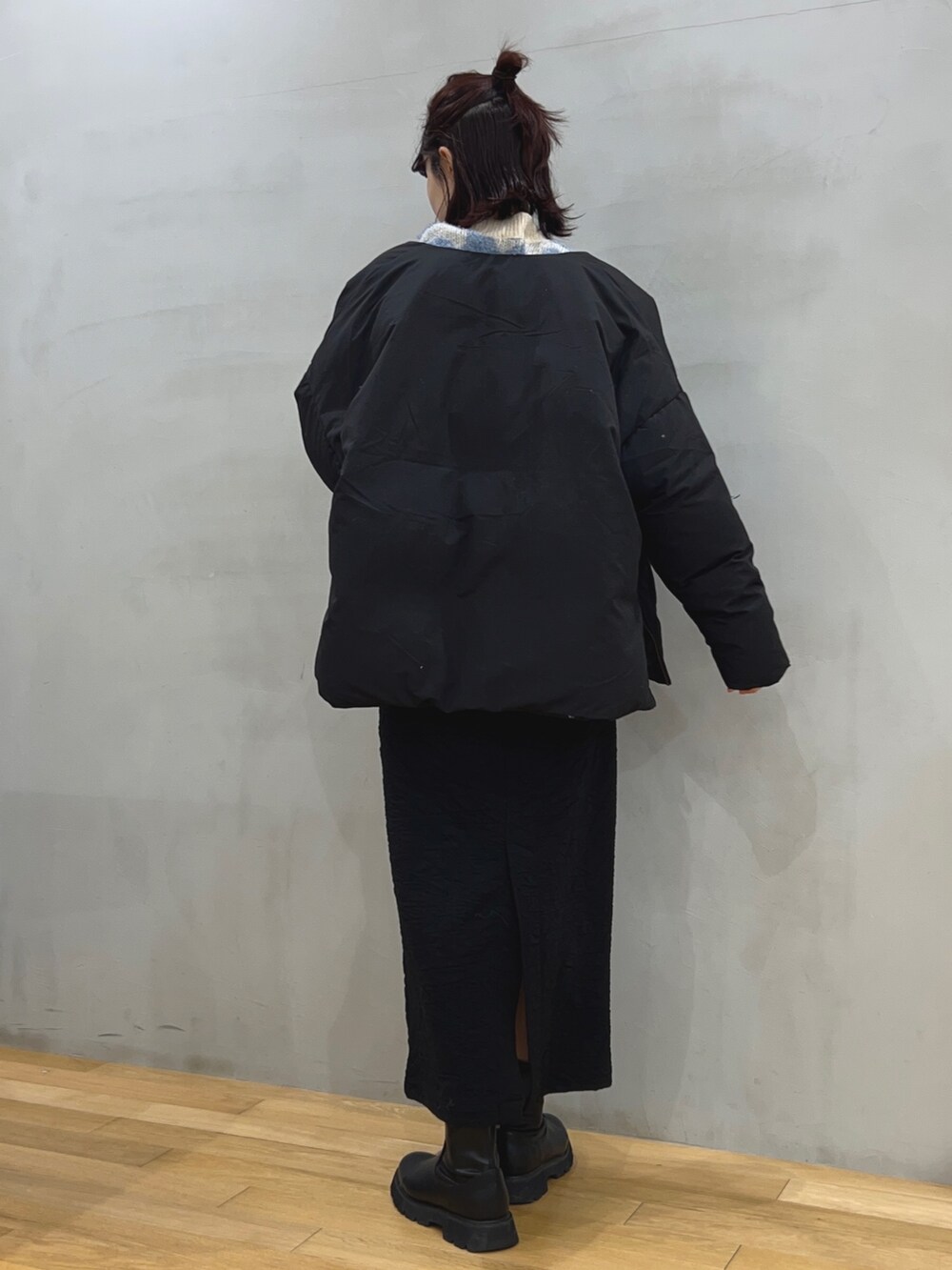 ブラック系のスカート、ブルー系のニット/セーター、ブラック系のダウンジャケット/コートを着用したレディースの冬コーディネートの2枚目の写真