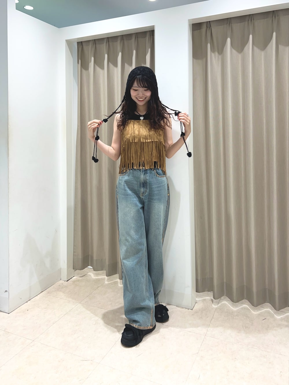 ブラック系のタンクトップ、ブルー系のデニムパンツ、イエロー系のキャミソールを着用したレディースの夏コーディネートの2枚目の写真