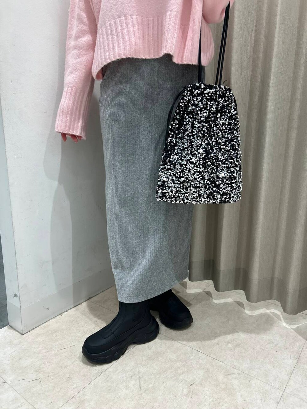 シルバー系のトートバッグ、グレー系のスカート、ブラック系のブーツを着用したレディースの冬コーディネートの4枚目の写真