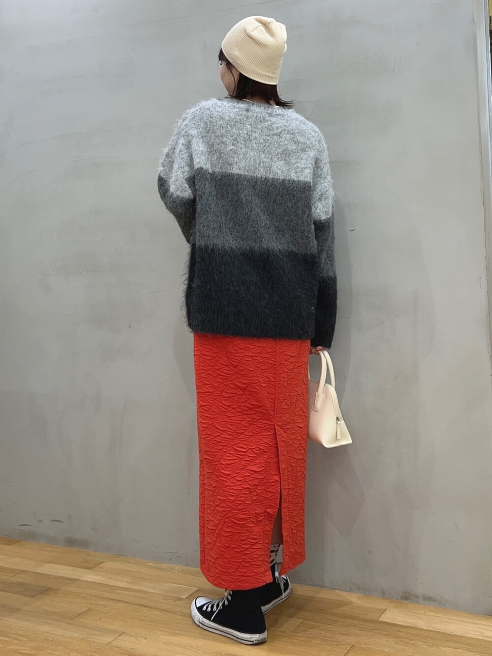 グレー系のニット/セーター、レッド系のスカート、イエロー系のショルダーバッグを着用したレディースの冬コーディネートの2枚目の写真