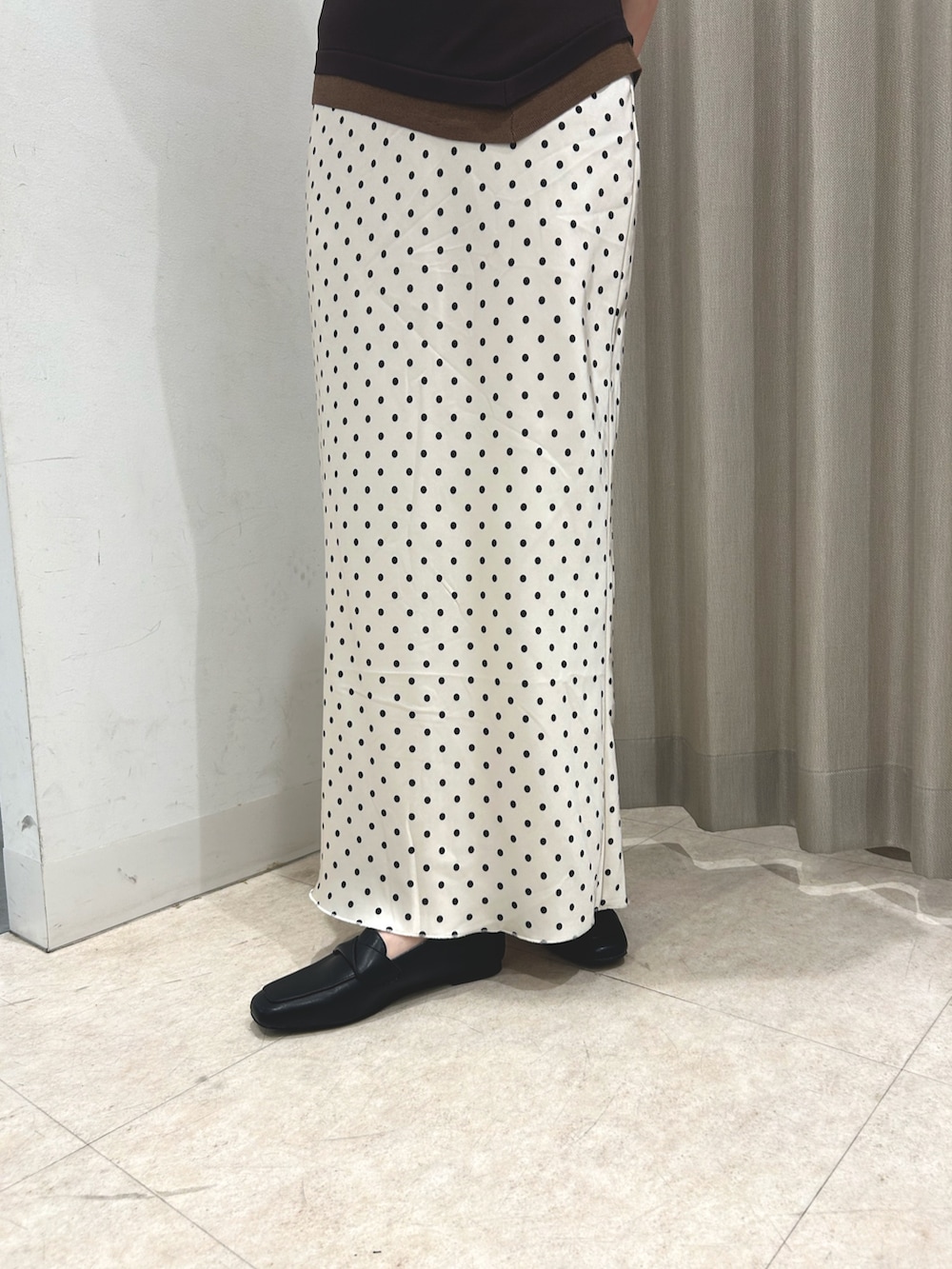 ブラウン系のニット/セーター、ホワイト系のスカート、ブラック系のローファーを着用したレディースの春コーディネートの4枚目の写真