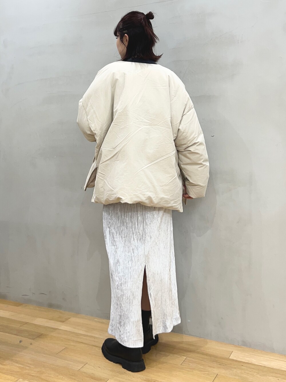 グレー系のスカート、ベージュ系のダウンジャケット/コート、グレー系のカーディガン/ボレロを着用したレディースの冬コーディネートの2枚目の写真