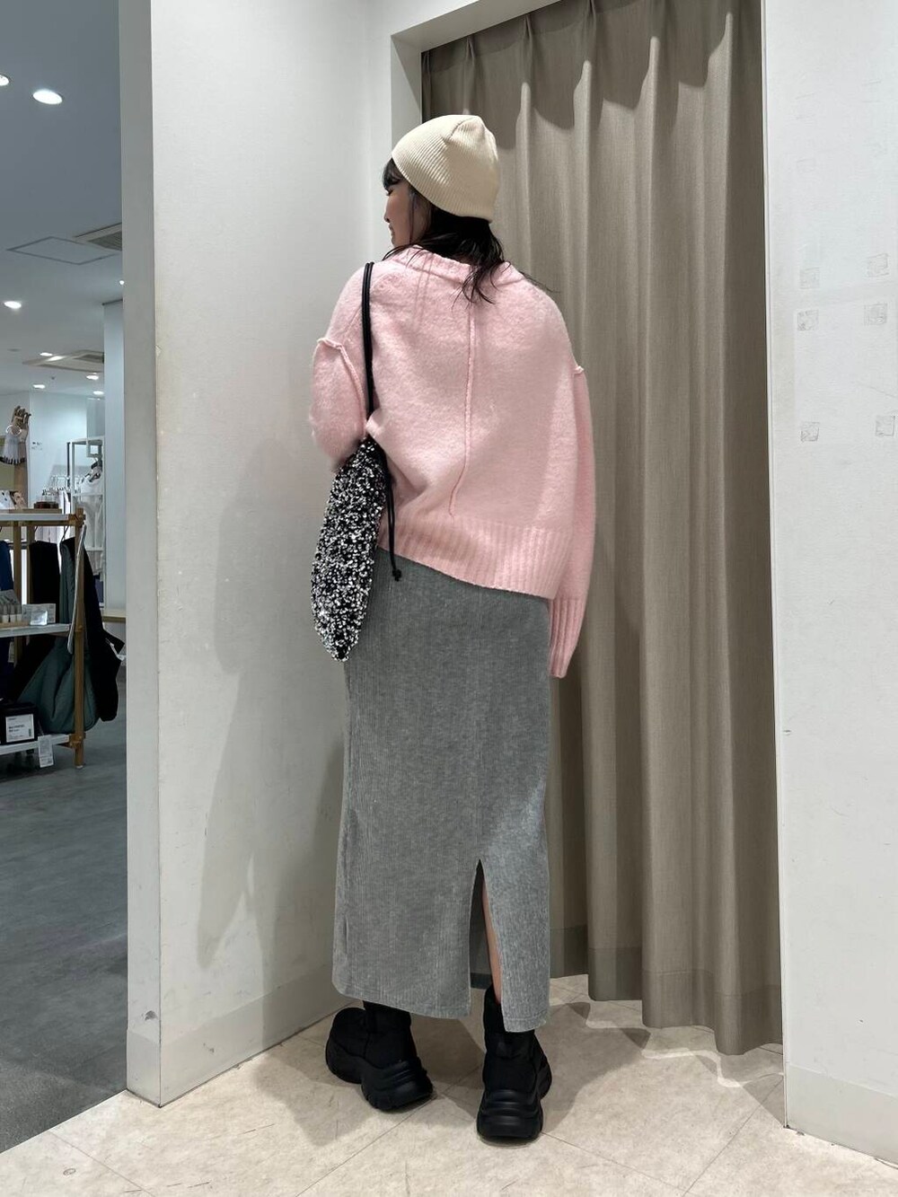 シルバー系のトートバッグ、グレー系のスカート、ブラック系のブーツを着用したレディースの冬コーディネートの2枚目の写真