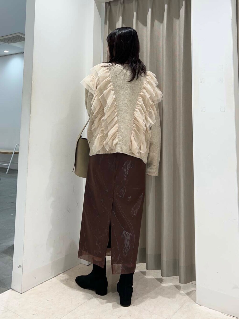 ベージュ系のハンドバッグ、ブラック系のブーツ、ブラウン系のスカートを着用したレディースの冬コーディネートの2枚目の写真