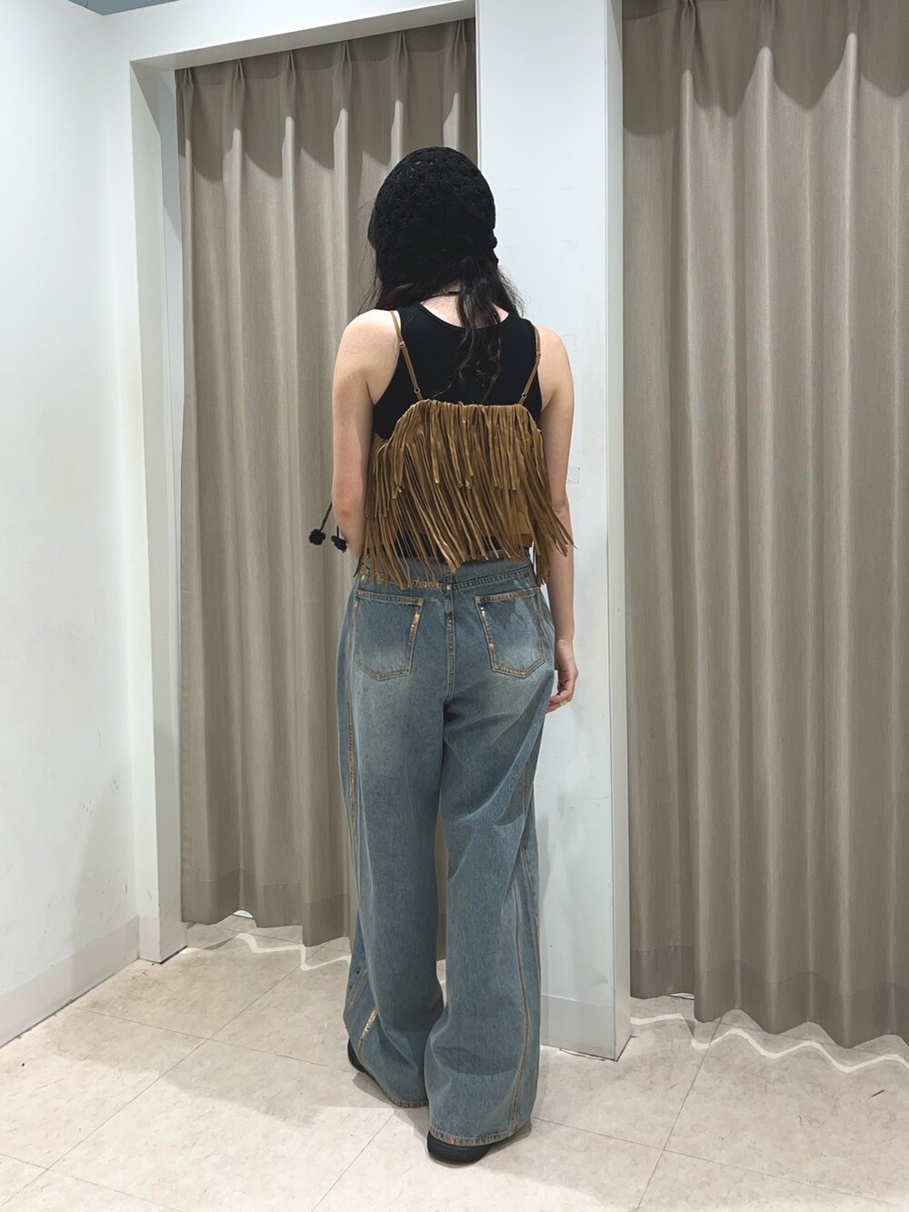 ブラック系のタンクトップ、ブルー系のデニムパンツ、イエロー系のキャミソールを着用したレディースの夏コーディネートの3枚目の写真