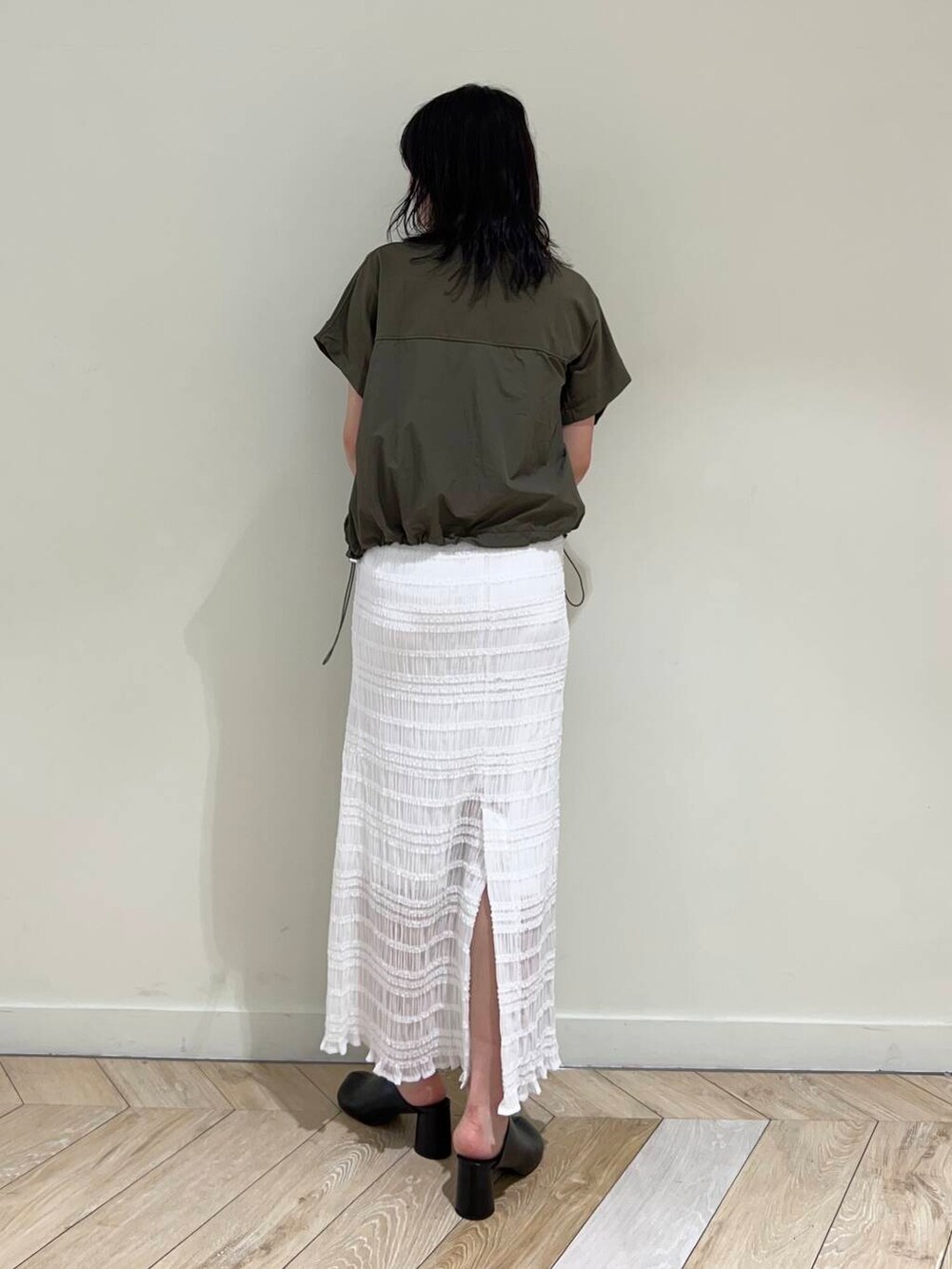 ホワイト系のスカート、ブラック系のサンダル、グリーン系のTシャツ/カットソーを着用したレディースの夏コーディネートの2枚目の写真