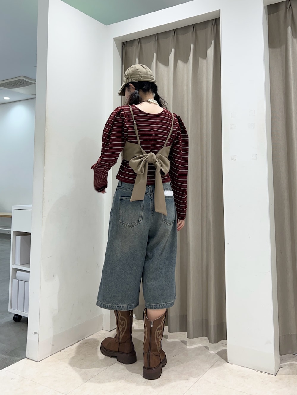 レッド系のカーディガン/ボレロ、ブルー系のデニムパンツを着用したレディースの秋コーディネートの2枚目の写真