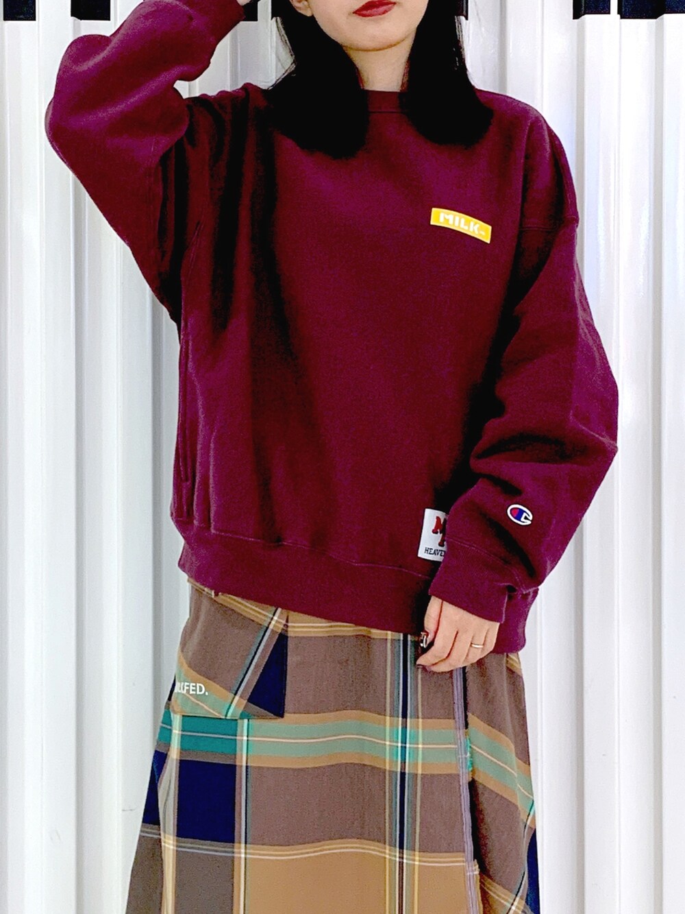 レッド系のスウェット、ベージュ系のスカート、ブラウン系のキャップを着用したレディースの秋コーディネートの5枚目の写真