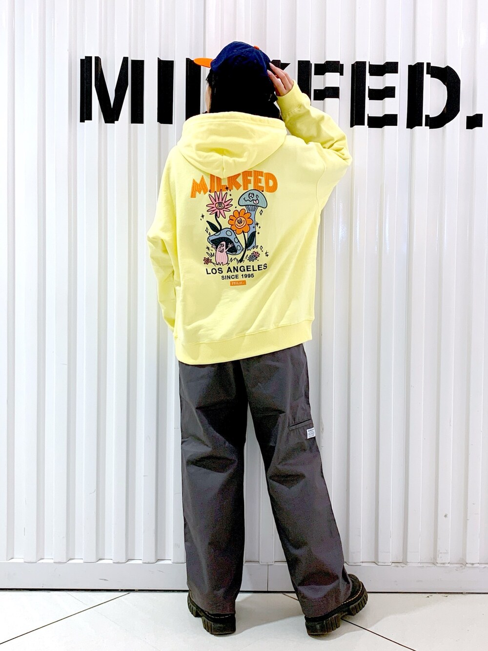 グレー系のその他パンツ、イエロー系のパーカー、オレンジ系のキャップを着用したレディースの冬コーディネートの2枚目の写真