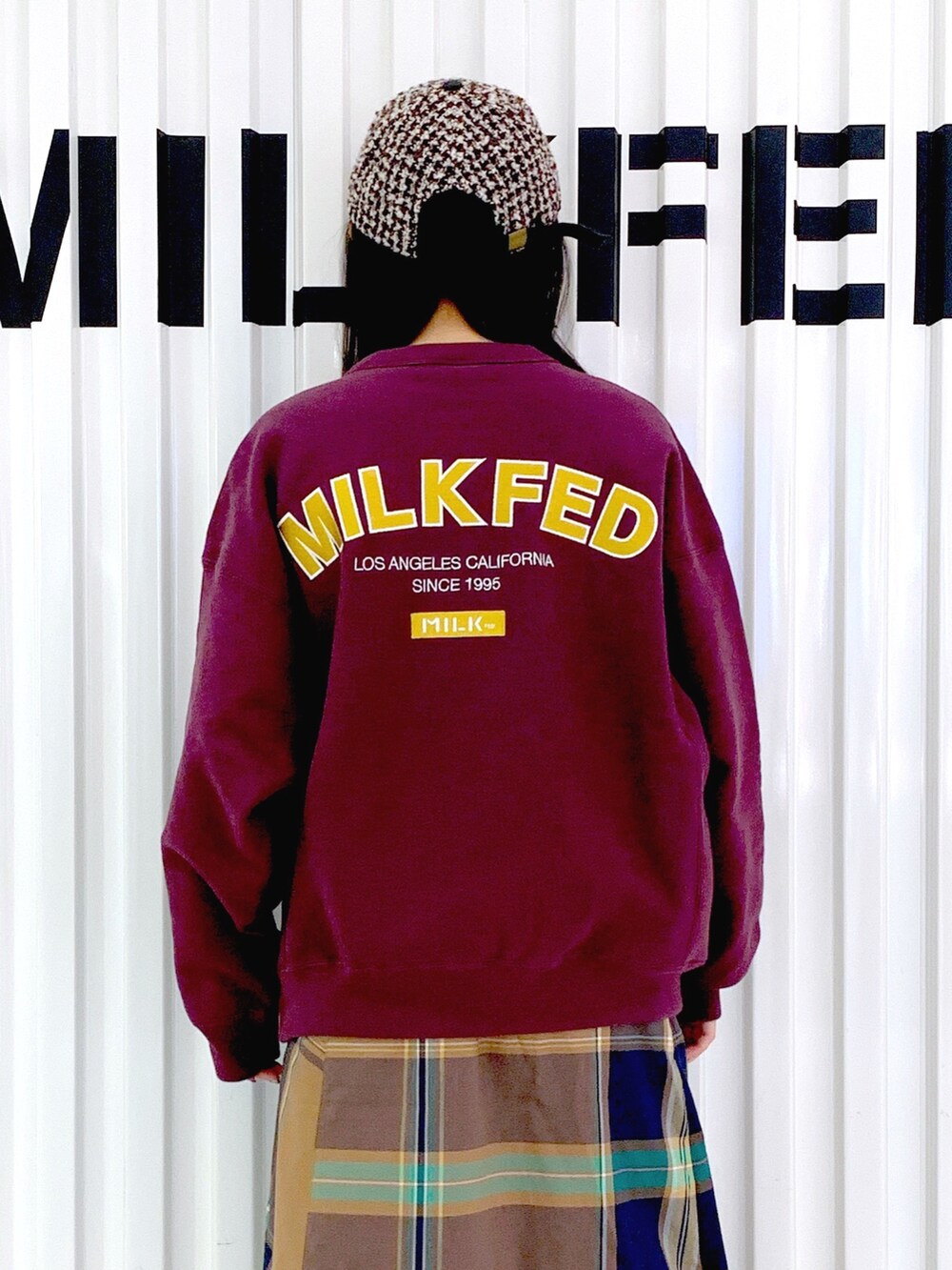 レッド系のスウェット、ベージュ系のスカート、ブラウン系のキャップを着用したレディースの秋コーディネートの4枚目の写真