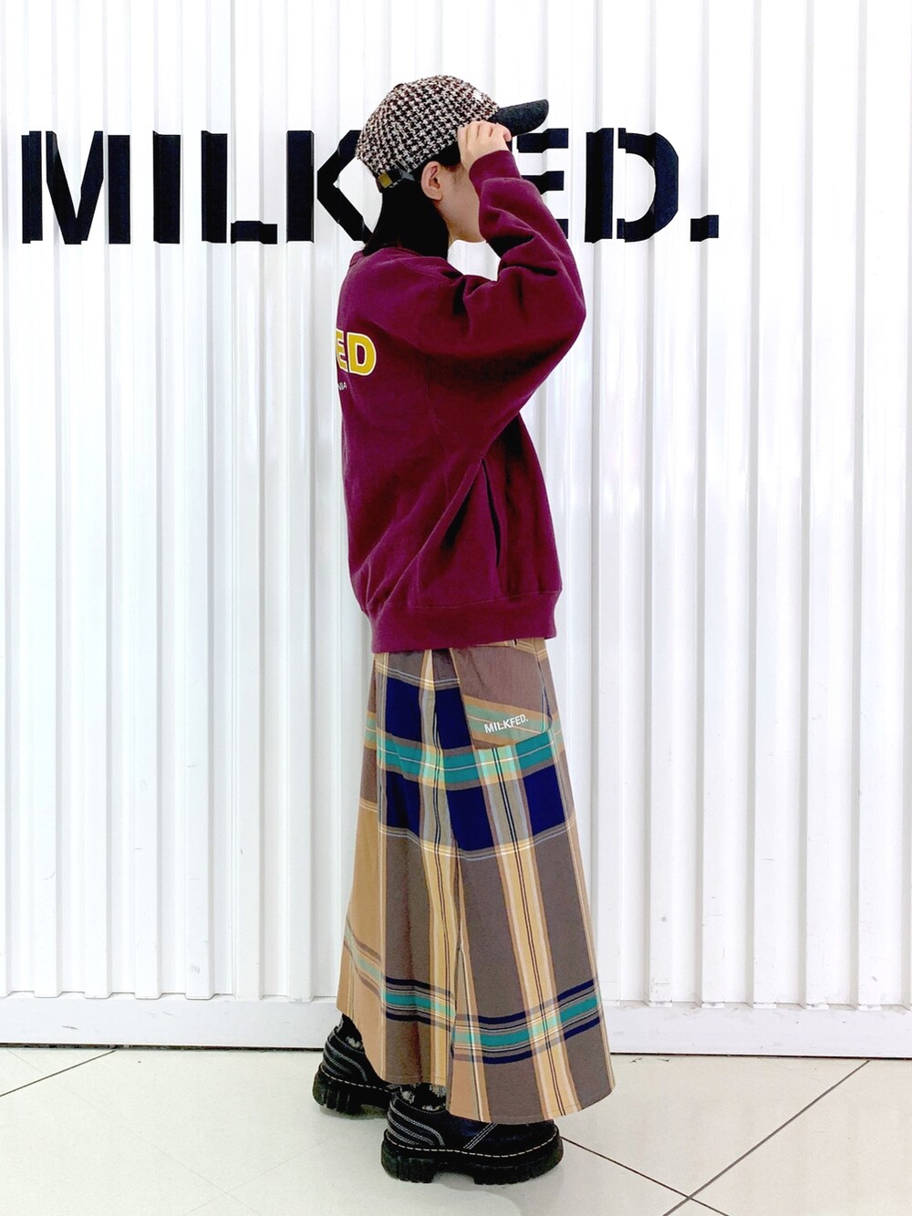 レッド系のスウェット、ベージュ系のスカート、ブラウン系のキャップを着用したレディースの秋コーディネートの3枚目の写真