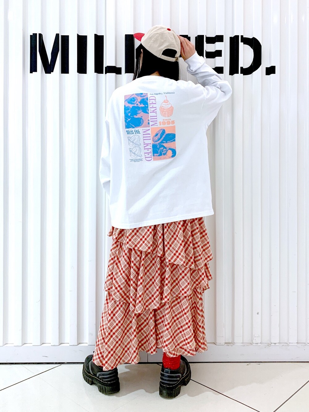 ホワイト系のTシャツ/カットソー、レッド系のスカート、レッド系のキャップを着用したレディースの冬コーディネートの4枚目の写真