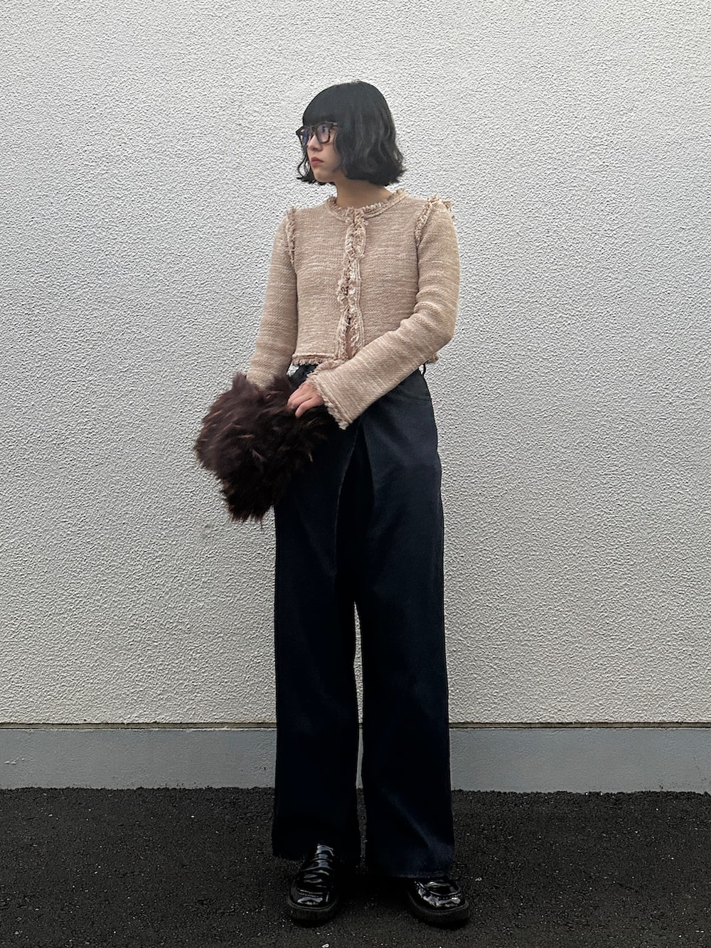 ブルー系のデニムパンツ、ブラウン系のクラッチバッグ、ブラック系のシューズを着用したレディースの冬コーディネートの2枚目の写真