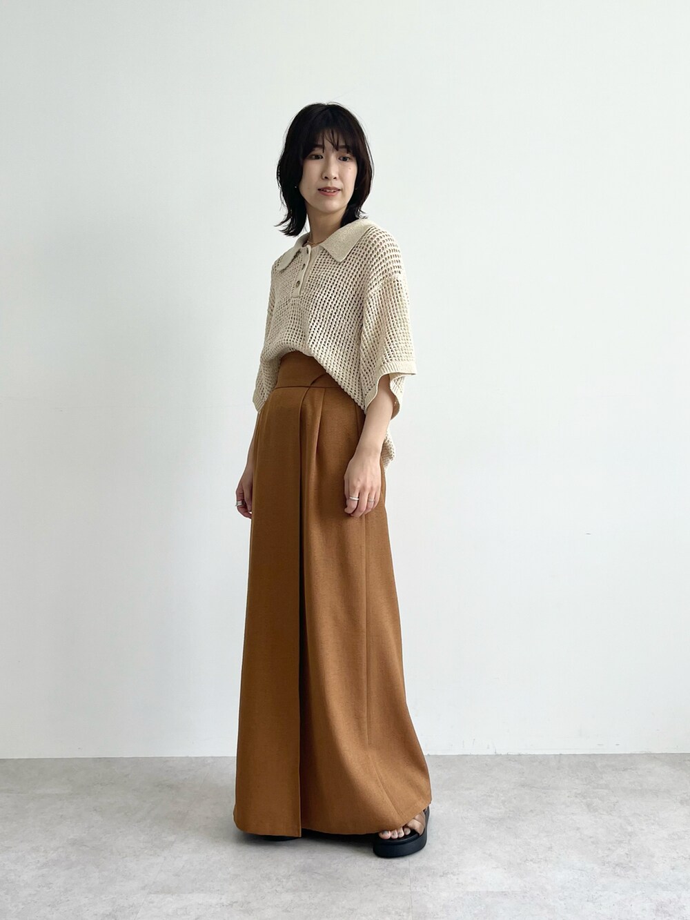 ブラック系のニット/セーター、イエロー系のスカート、ベージュ系のニット/セーターを着用したレディースの春コーディネートの2枚目の写真