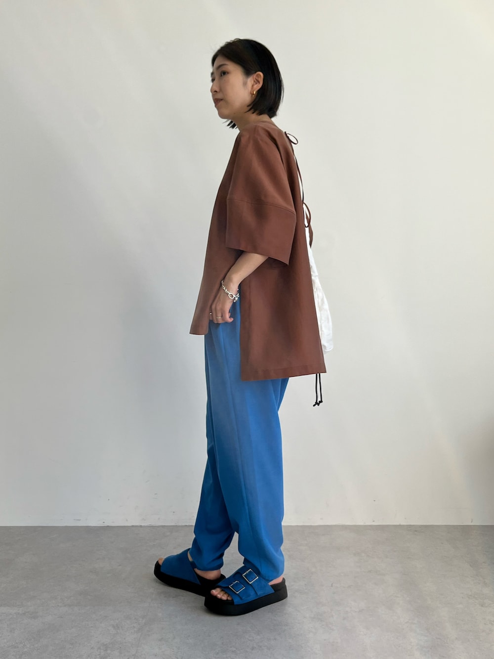 ブラウン系のシャツ/ブラウス、ブルー系のその他パンツ、ホワイト系のショルダーバッグを着用したレディースの春コーディネートの2枚目の写真