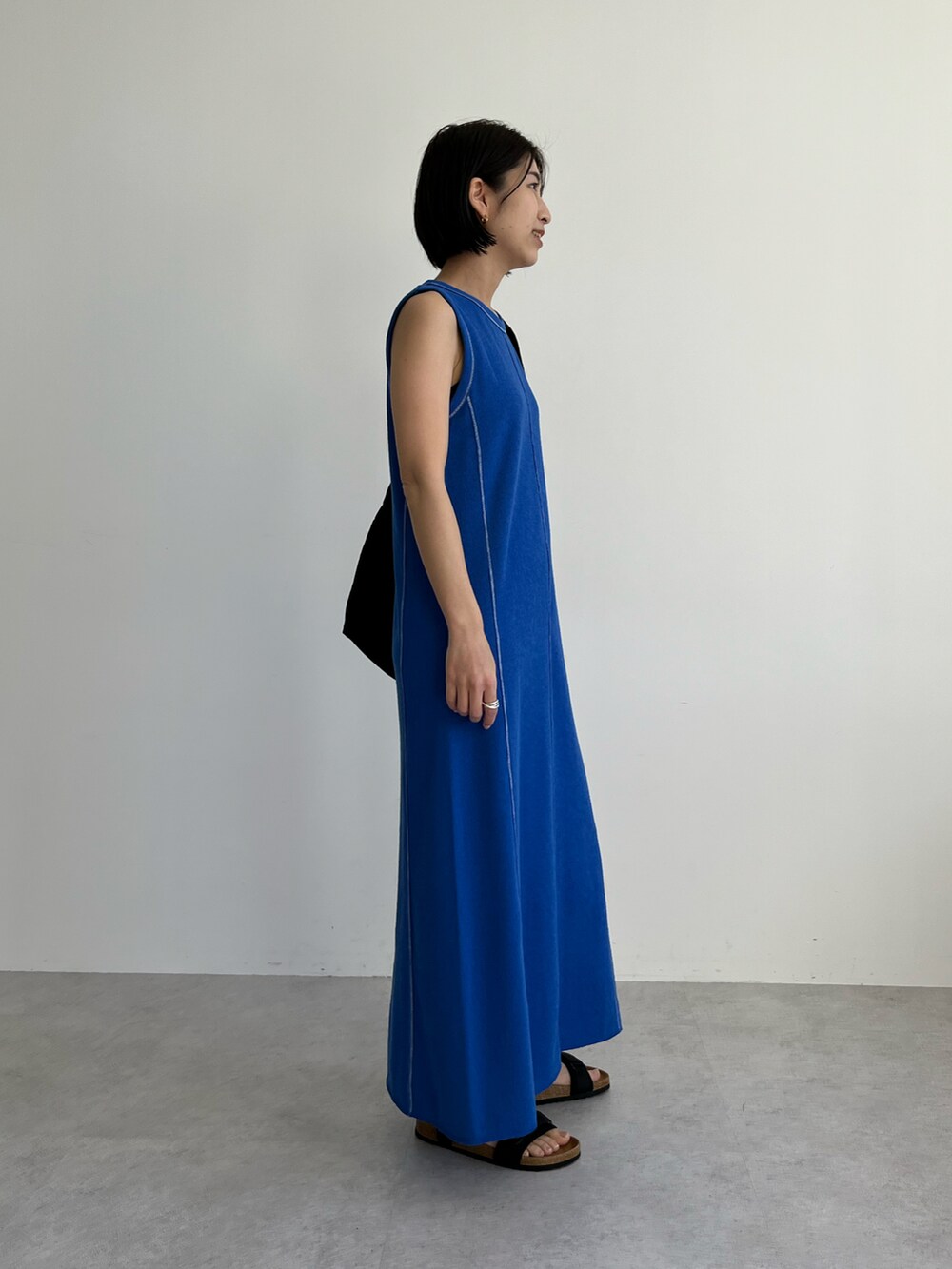 ブルー系のワンピース、ブラック系のショルダーバッグ、ブラック系のサンダルを着用したレディースの春コーディネートの2枚目の写真