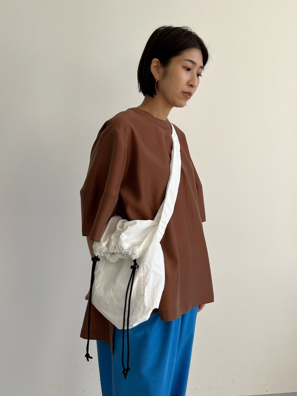 ブラウン系のシャツ/ブラウス、ブルー系のその他パンツ、ホワイト系のショルダーバッグを着用したレディースの春コーディネートの4枚目の写真