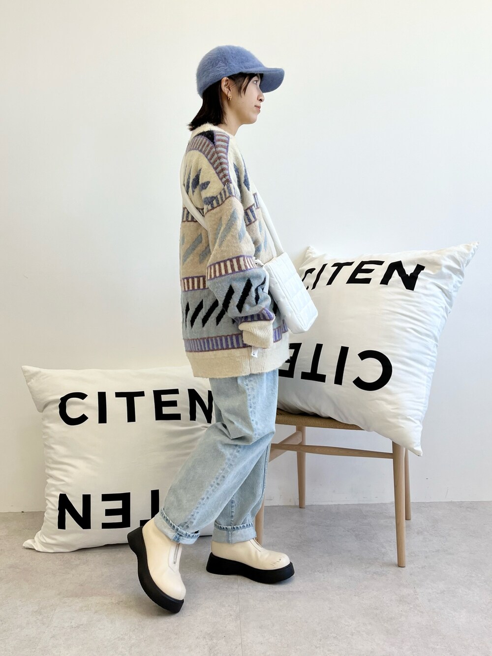 ホワイト系のショルダーバッグ、ブルー系のニット/セーター、ブルー系のデニムパンツを着用したレディースの秋コーディネートの2枚目の写真