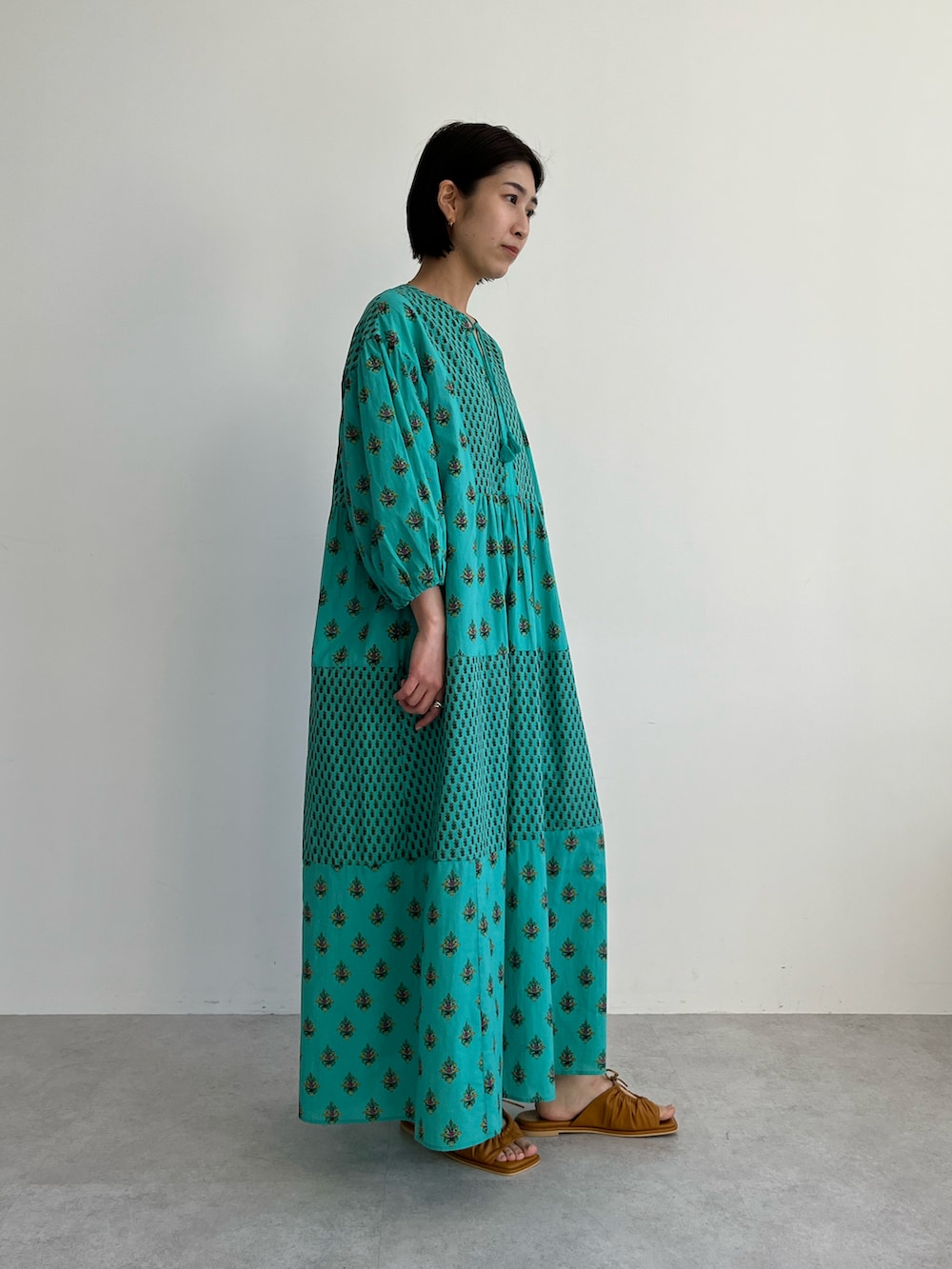 グリーン系のワンピース、ブラウン系のサンダルを着用したレディースの春コーディネートの2枚目の写真