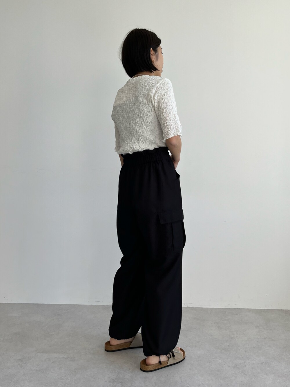 ホワイト系のTシャツ/カットソー、ブラック系のカーゴパンツ、ベージュ系のサンダルを着用したレディースの春コーディネートの2枚目の写真