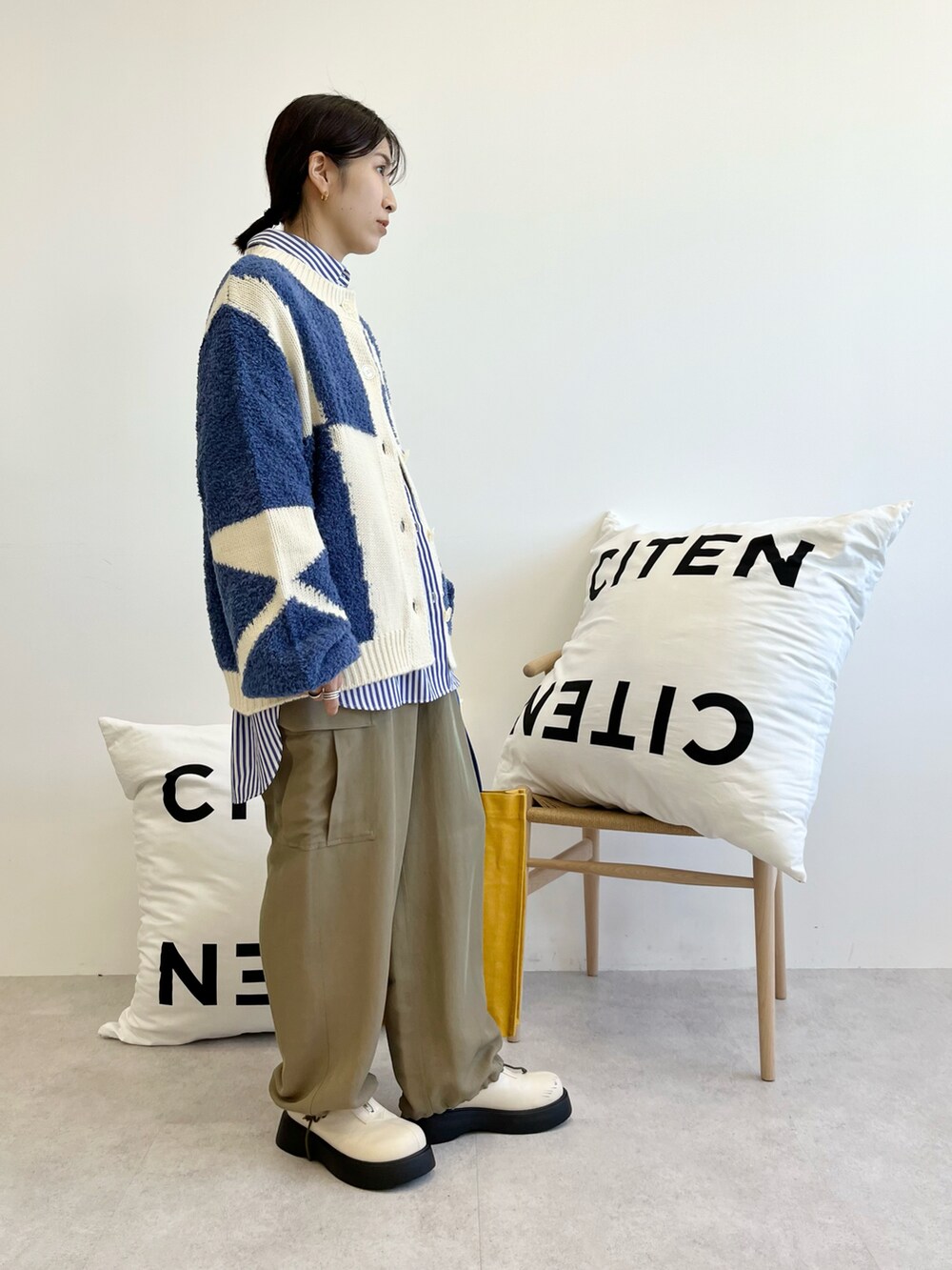 ホワイト系のトートバッグ、ホワイト系のブーツ、グリーン系のカーゴパンツを着用したレディースの秋コーディネートの2枚目の写真