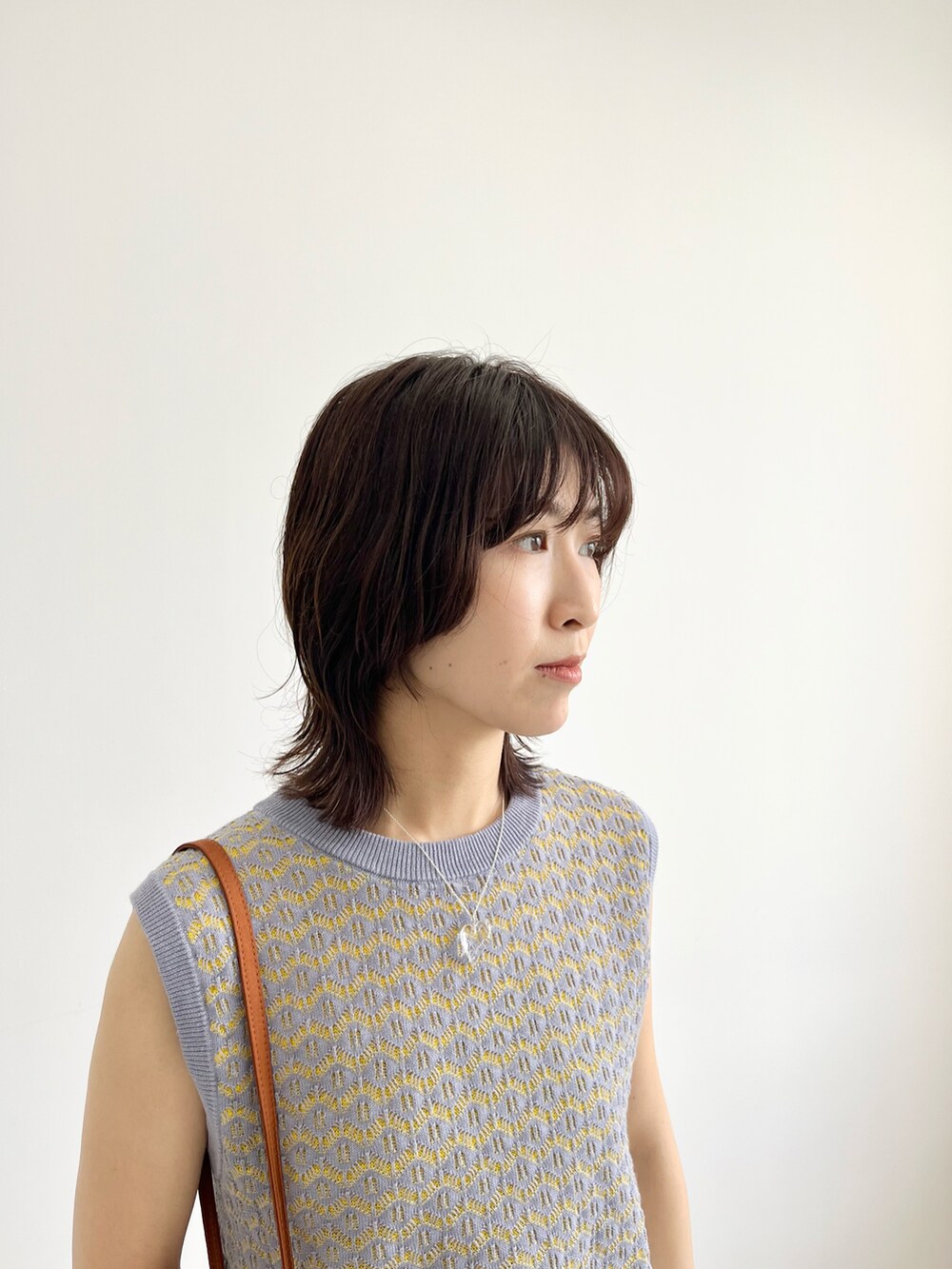 ブルー系のベスト、ブラウン系のショルダーバッグ、ホワイト系のその他パンツを着用したレディースの春コーディネートの4枚目の写真