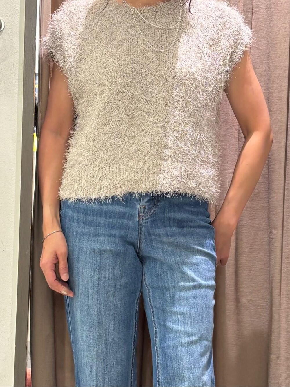 ベージュ系のニット/セーター、ブルー系のデニムパンツ、シルバー系のネックレスを着用したレディースの秋コーディネートの4枚目の写真