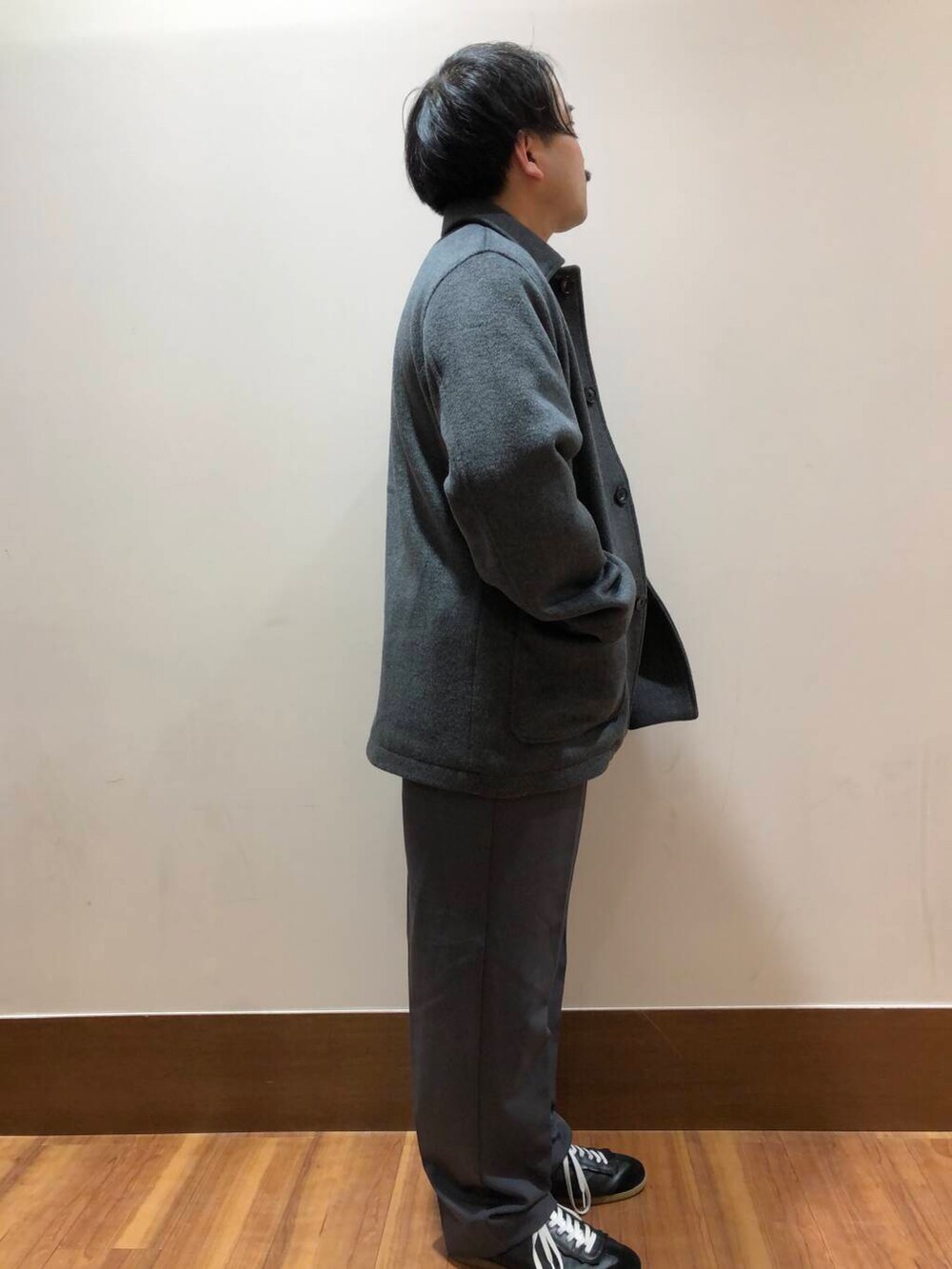 グレー系のその他パンツ、オレンジ系のニット/セーター、グレー系のステンカラーコートを着用したメンズの冬コーディネートの2枚目の写真