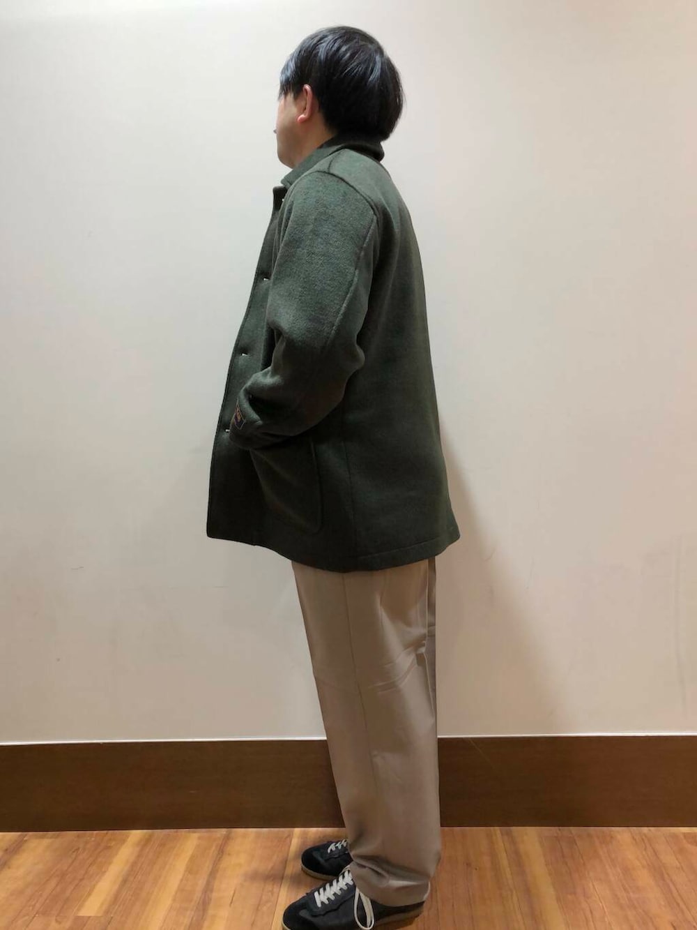 ベージュ系のその他パンツ、ブラック系のニット/セーター、グリーン系のステンカラーコートを着用したメンズの冬コーディネートの4枚目の写真