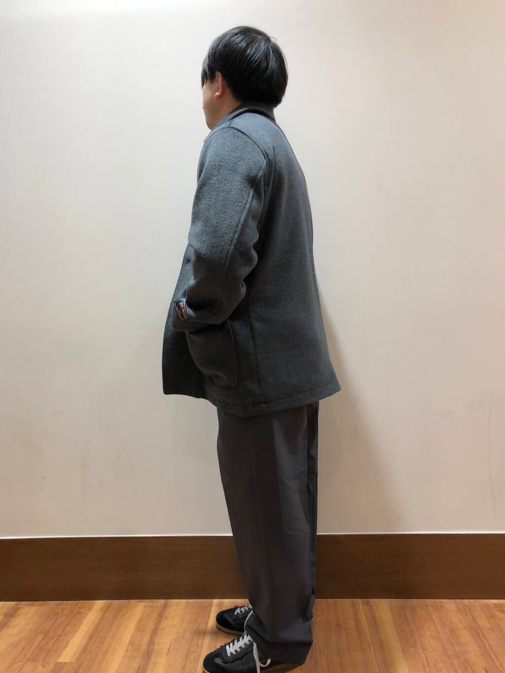 グレー系のその他パンツ、オレンジ系のニット/セーター、グレー系のステンカラーコートを着用したメンズの冬コーディネートの4枚目の写真