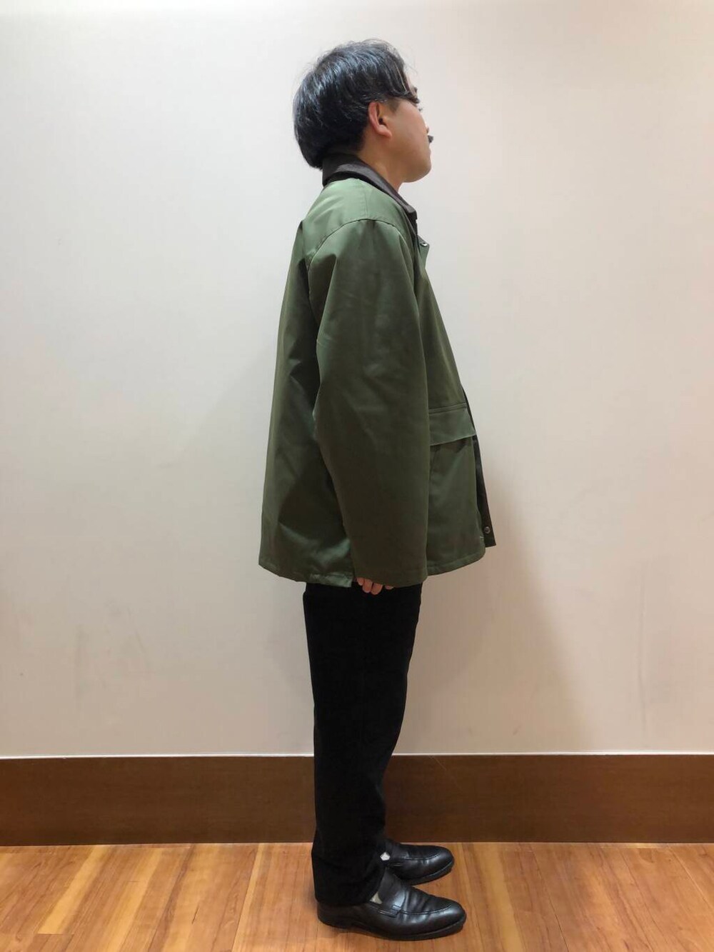 グリーン系のミリタリージャケット、ベージュ系のスウェット、ブラック系のその他パンツを着用したメンズの秋コーディネートの2枚目の写真