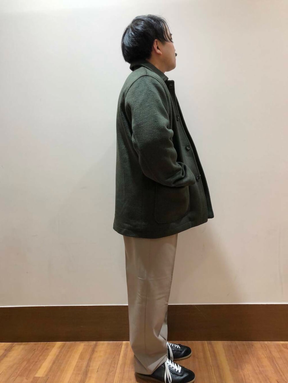 ベージュ系のその他パンツ、ブラック系のニット/セーター、グリーン系のステンカラーコートを着用したメンズの冬コーディネートの2枚目の写真