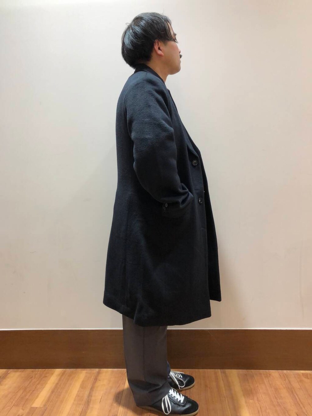 グレー系のその他パンツ、オレンジ系のニット/セーター、ブラック系のその他アウターを着用したメンズの冬コーディネートの2枚目の写真