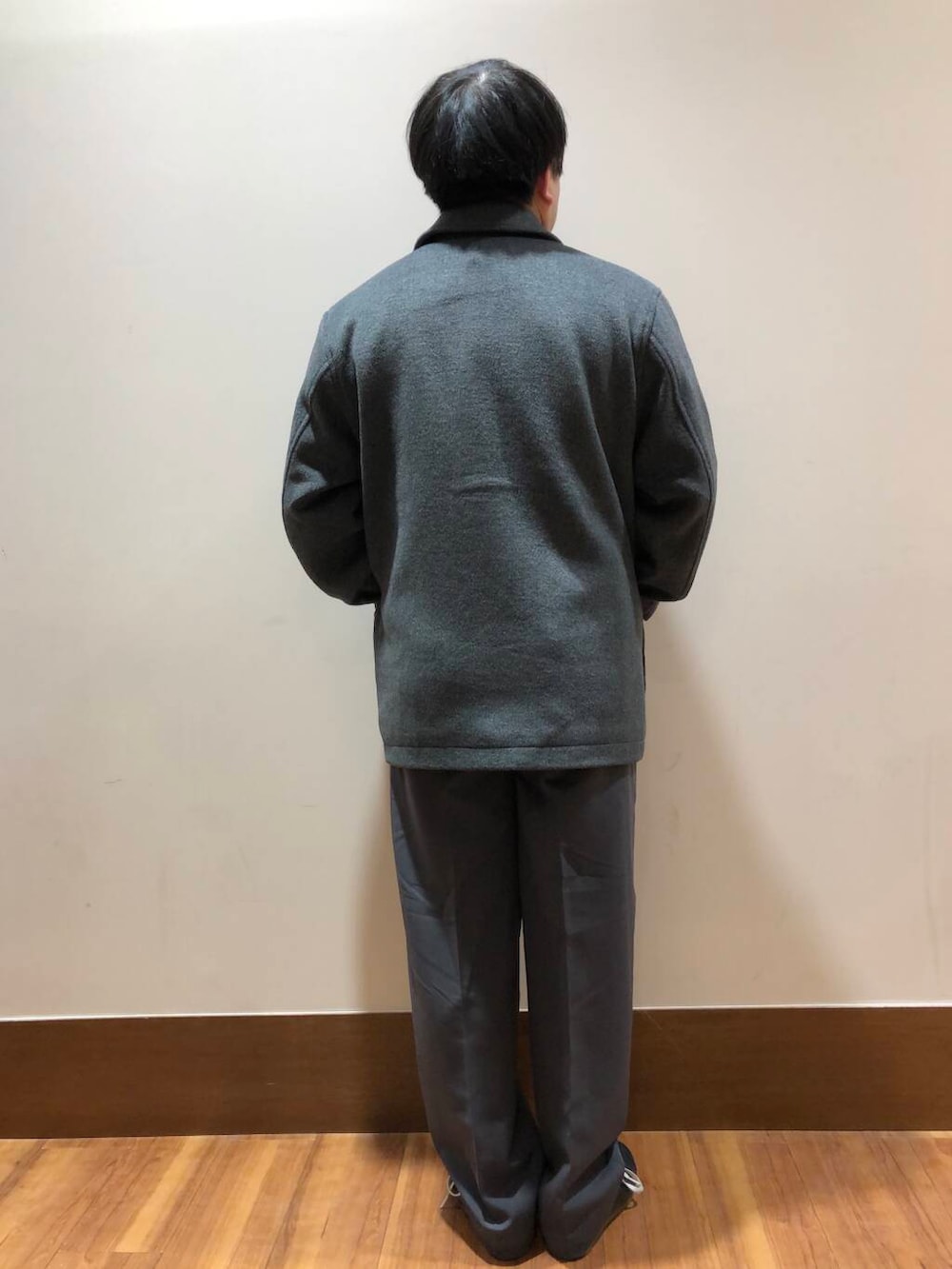 グレー系のその他パンツ、オレンジ系のニット/セーター、グレー系のステンカラーコートを着用したメンズの冬コーディネートの3枚目の写真