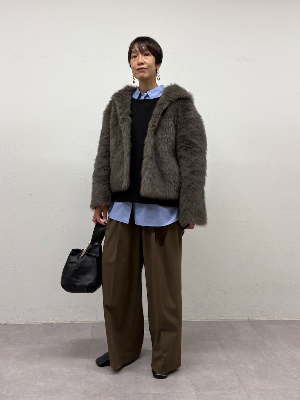 グレー系のベスト、ブルー系のシャツ/ブラウス、ブラック系のTシャツ/カットソーを着用したレディースの秋コーディネートの2枚目の写真