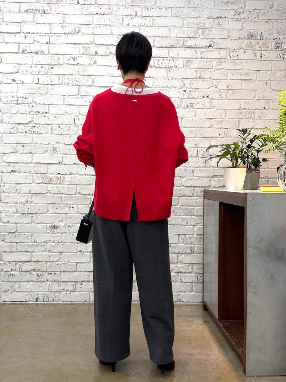 レッド系のニット/セーター、グレー系のTシャツ/カットソー、ブラック系のショルダーバッグを着用したレディースの秋コーディネートの3枚目の写真