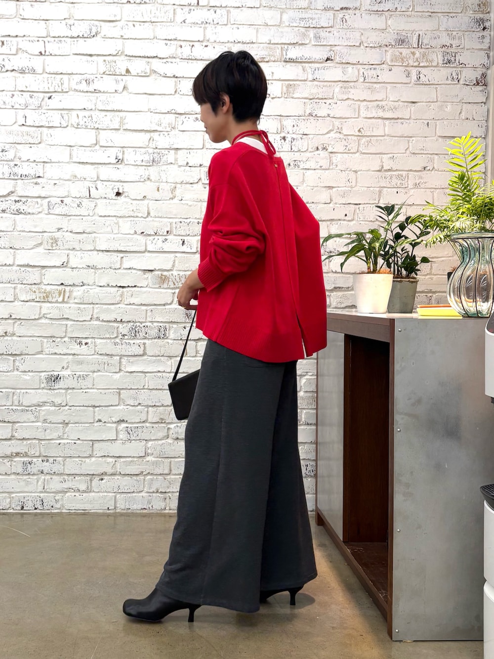 レッド系のニット/セーター、グレー系のTシャツ/カットソー、ブラック系のショルダーバッグを着用したレディースの秋コーディネートの4枚目の写真