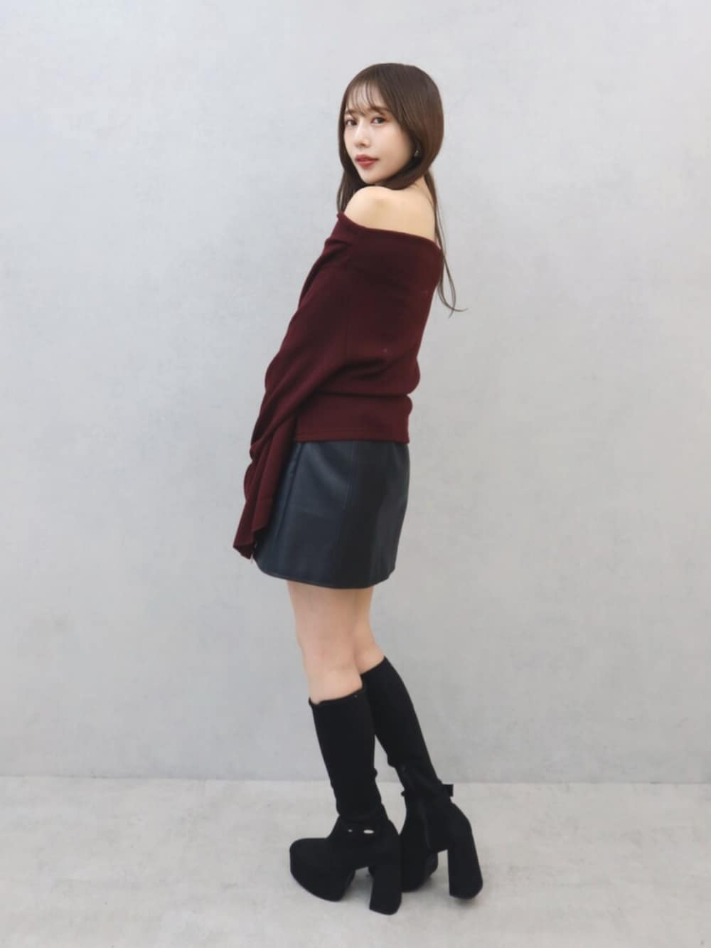 レッド系のTシャツ/カットソー、ブラック系のスカート、ブラック系のブーツを着用したレディースの秋コーディネートの3枚目の写真