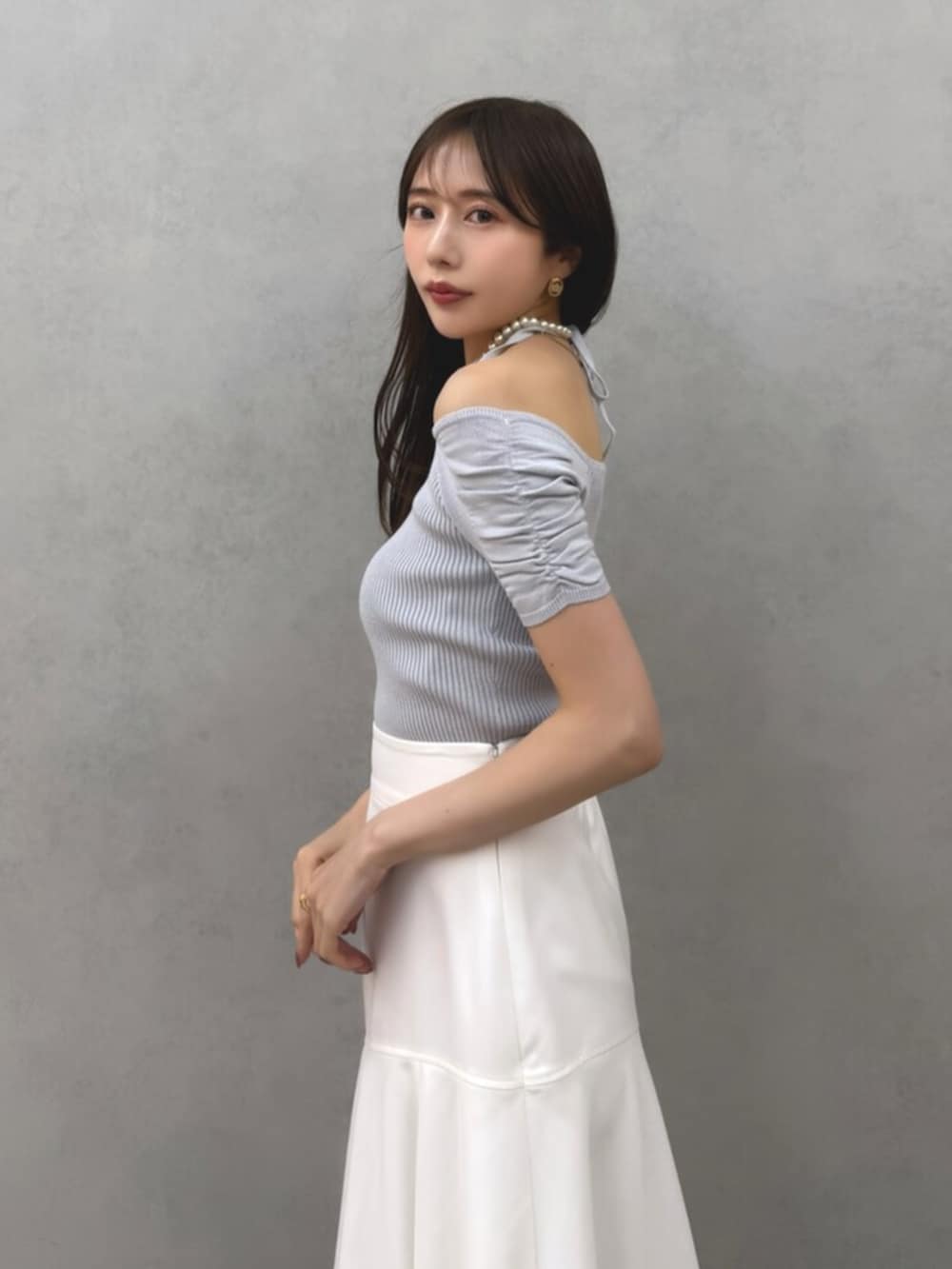 ブルー系のニット/セーター、ホワイト系のスカート、ブラック系のパンプスを着用したレディースの春コーディネートの2枚目の写真